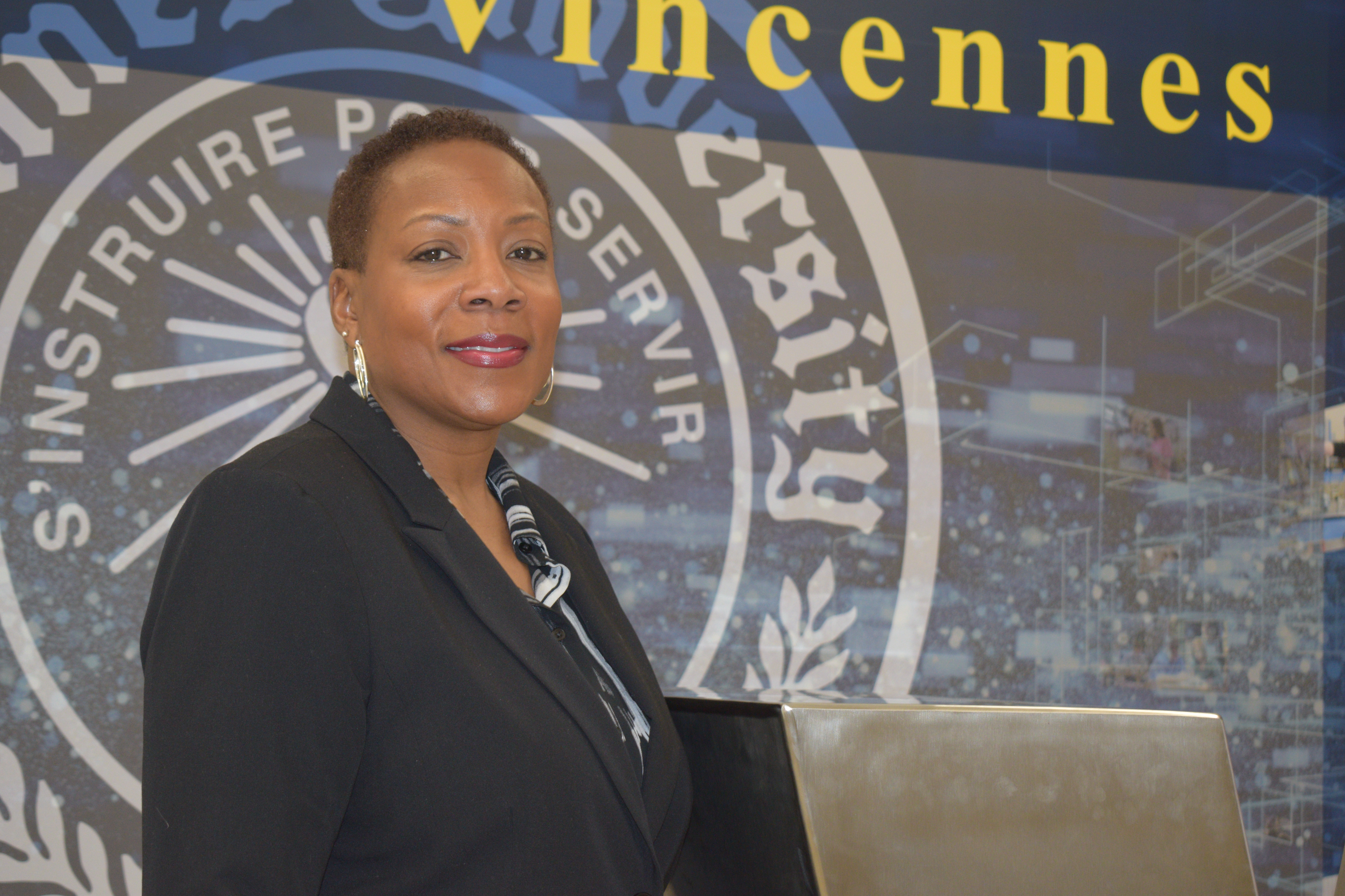 Dr. Nicole Shankle wearing professional clothing with a Vincennes University mural behind her